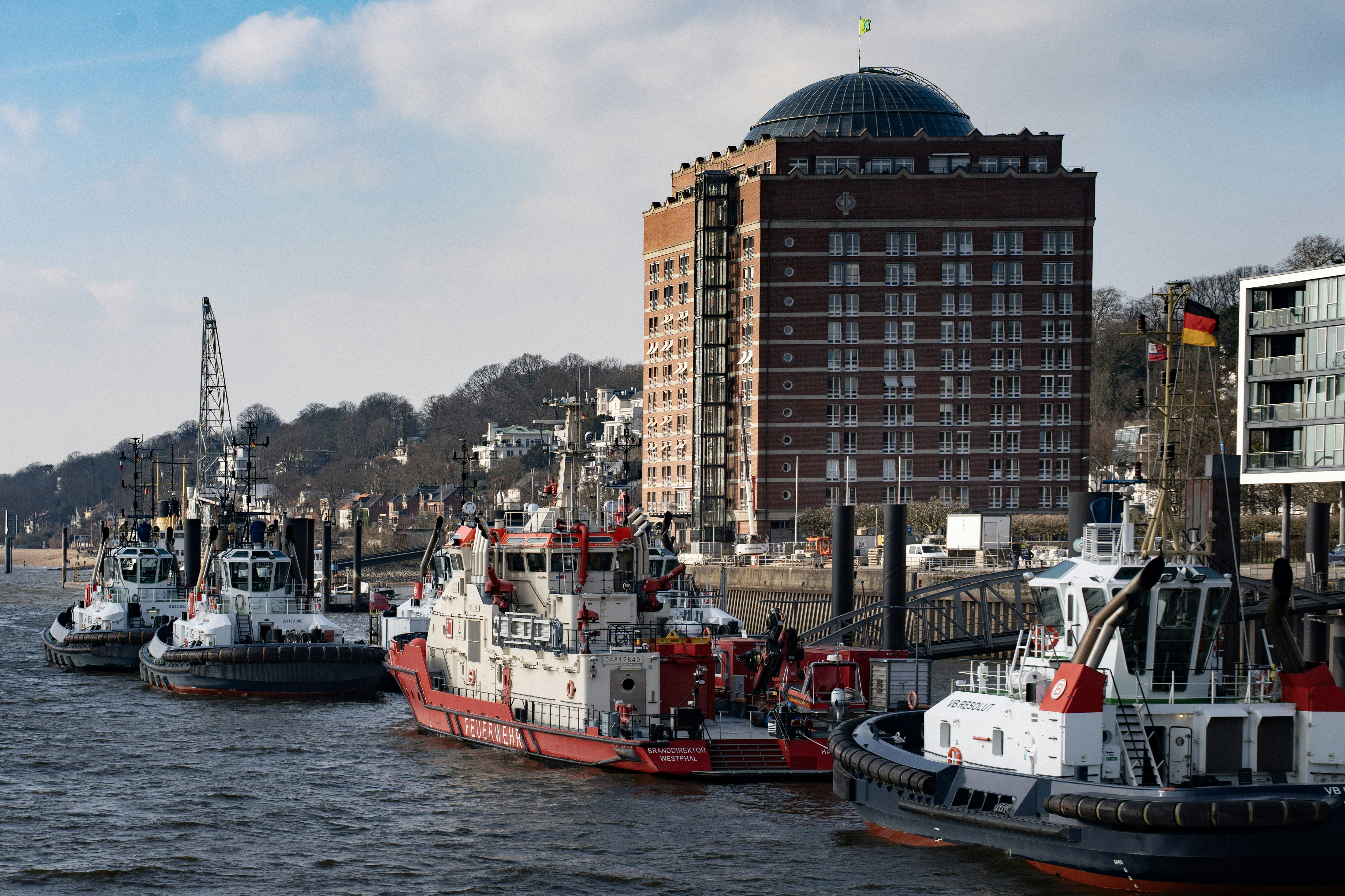 Boats are docked by a large brick building.